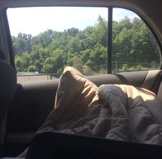 an unmade bed sitting in the back of a car next to a large window