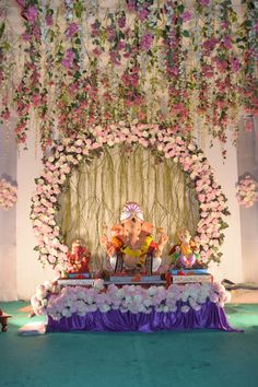 an elephant statue sitting on top of a stage with flowers hanging from it's ceiling