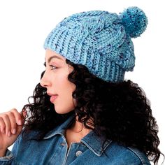 a woman with curly hair wearing a denim jacket and a knitted pom - pom hat