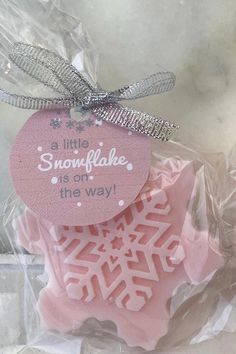 a pink snowflake is on the way ornament in plastic wrapper