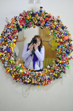 a woman taking a photo in front of a mirror covered with toy figurines