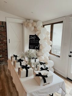 the table is set up with white balloons and gift boxes for guests to take home