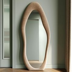 an oval shaped mirror sitting on top of a wooden floor next to a door way