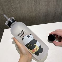 someone is holding a water bottle with a cartoon character on it and the lid has a black cap