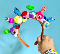 a hand is holding a colorful headband made out of stuffed animals and other toys