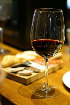 a glass of wine sitting on top of a wooden table