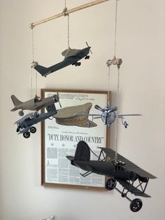 several toy airplanes hanging from the ceiling in a room with a poster on the wall