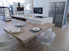 a modern kitchen with an island and dining table set for four in front of the stairs