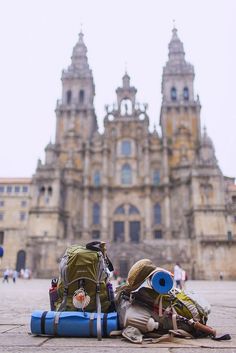 backpacks and other items lay on the ground in front of an old castle like building