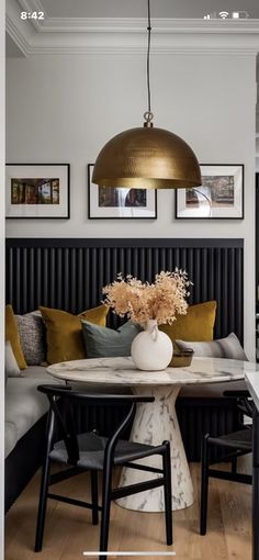 a dining room table with chairs and a vase filled with flowers on top of it