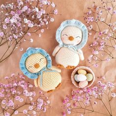 three crocheted stuffed animals sitting next to each other in front of pink flowers