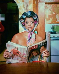 a woman is reading a magazine while sitting at a table with her head covered in hair