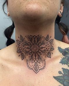 a woman with a tattoo on her neck is looking at the camera and has an intricate design