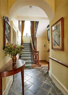 an entry way leading to a hallway with stairs and potted plants on the table