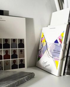 an open book sitting on top of a white desk next to a stack of books