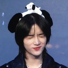 a person with a panda hat on their head and wearing a black leather jacket is looking at the camera