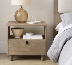 a bedside table with a lamp and books on it