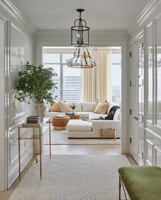 a living room filled with furniture and a chandelier hanging over the top of it