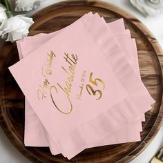 pink napkins with gold foil on them sitting on top of a wooden platter