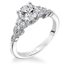 a white gold engagement ring with three stones on the side and an oval diamond center