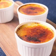 three small white bowls filled with food on top of a wooden tray