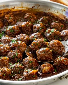 meatballs and gravy in a pot with a spoon