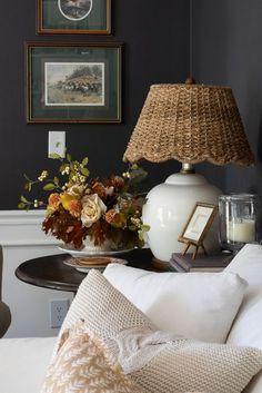 a white lamp sitting on top of a table next to a vase filled with flowers