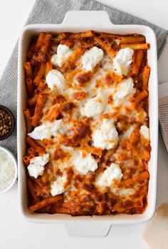 a white casserole dish filled with pasta and cheese on top of a table