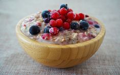 a wooden bowl filled with oatmeal and berries