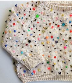 a white sweater with multicolored sequins on it