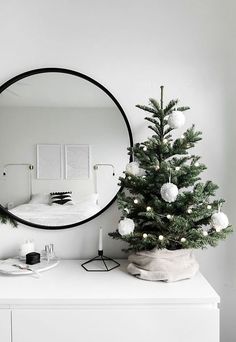 a white christmas tree in front of a round mirror