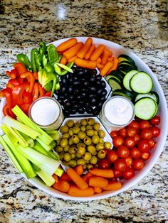 a plate filled with vegetables and dips sitting on top of a marble countertop