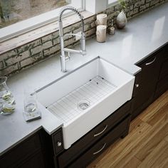 a kitchen sink sitting on top of a counter next to a window with potted plants