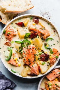 a bowl of salmon chowee with corn, green peppers and bread on the side