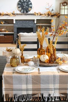 the table is set for thanksgiving dinner with pumpkins and gourds