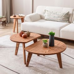 two wooden tables sitting on top of a white rug in front of a living room couch