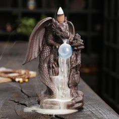 a statue of a dragon drinking water from a fountain with a bubble coming out of it