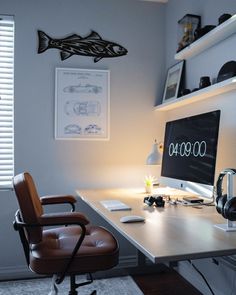 a computer desk with headphones on it and a chair in front of the monitor