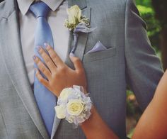 a close up of a person wearing a suit and tie with flowers on his lapel