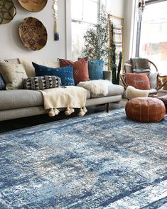 a living room filled with lots of furniture and pillows on top of a blue rug