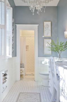 a white toilet sitting next to a bathroom sink under a light hanging from a chandelier