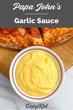 pizza with garlic sauce in a white bowl on a wooden cutting board next to a piece of bread