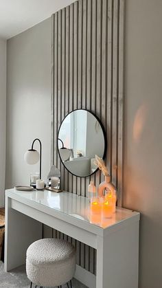 a dressing table with a mirror and stool next to it in front of a striped wall