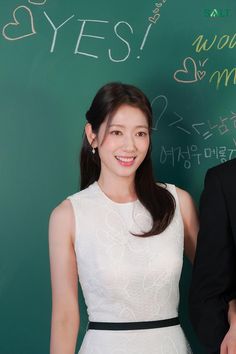 a man and woman standing next to each other in front of a chalkboard with writing on it