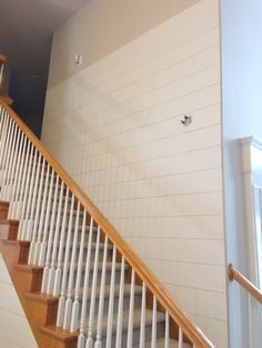 a staircase with white painted walls and wood handrails