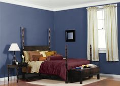 a bed room with a neatly made bed and blue walls