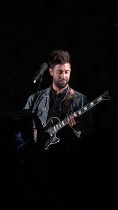 a man playing an electric guitar in the dark