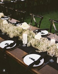 the table is set with black and white plates, silverware, and baby's breath flowers