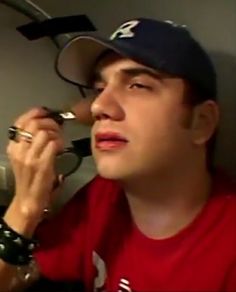 a man talking on a cell phone while wearing a baseball cap and holding a watch