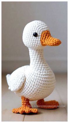 a crocheted duck sitting on top of a wooden floor next to a white wall